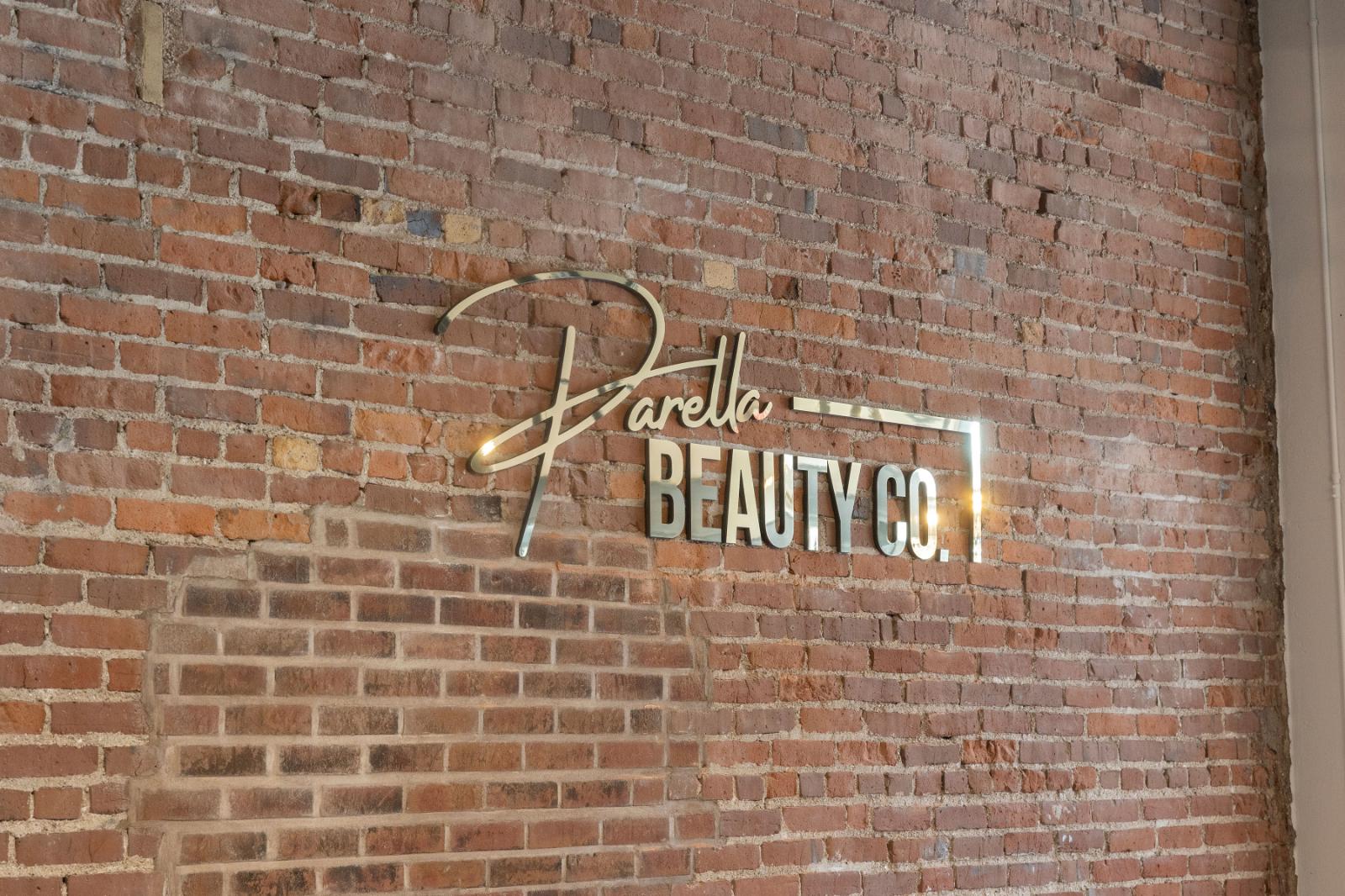 Parella Beauty Co logo in the salon on exposed brick wall
